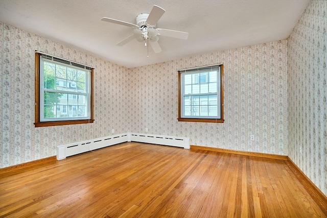 unfurnished room featuring hardwood / wood-style flooring, plenty of natural light, ceiling fan, and a baseboard radiator
