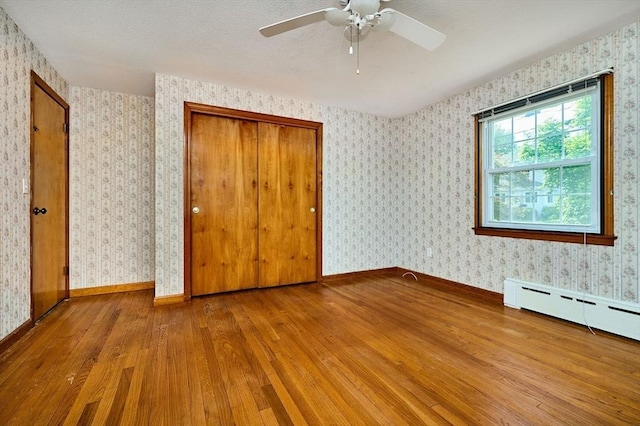 unfurnished bedroom with hardwood / wood-style floors, baseboards, wallpapered walls, a closet, and a ceiling fan