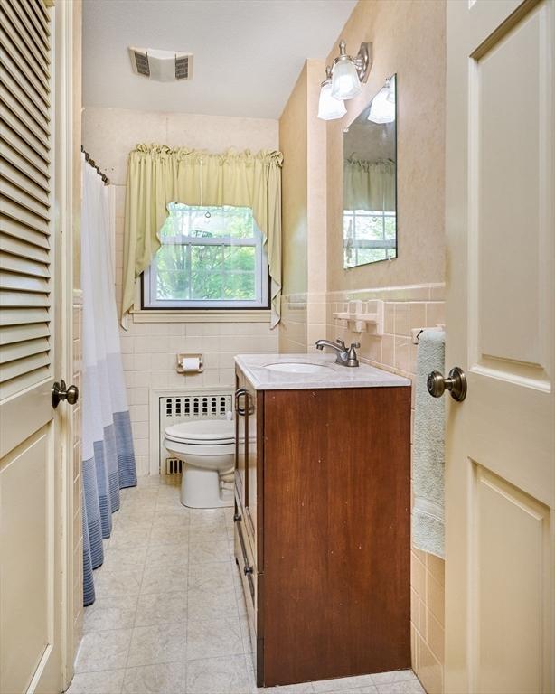 bathroom featuring tile walls, toilet, tile patterned flooring, radiator heating unit, and plenty of natural light