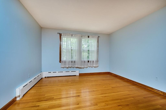 empty room featuring light wood-type flooring, baseboards, and baseboard heating