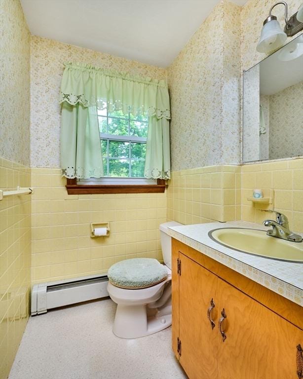 bathroom with a baseboard radiator, wallpapered walls, tile walls, wainscoting, and toilet