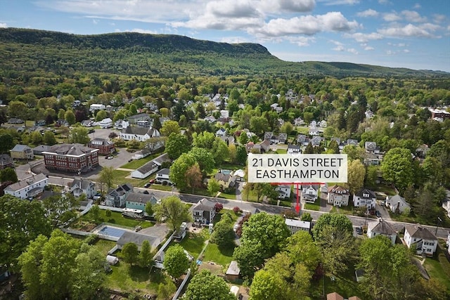 view of property location featuring a heavily wooded area, nearby suburban area, and a mountain backdrop
