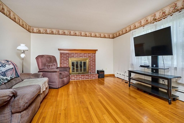 living area with light wood-style floors, a fireplace, and a baseboard heating unit