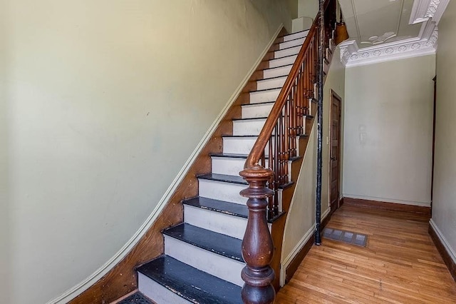 stairs featuring crown molding, baseboards, wood finished floors, and visible vents