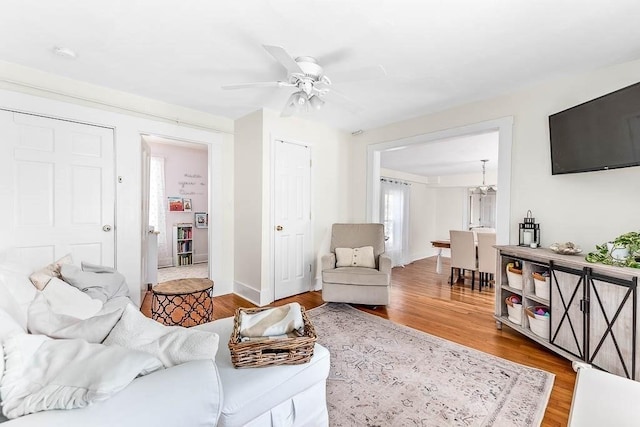 living area featuring baseboards, ceiling fan, and wood finished floors