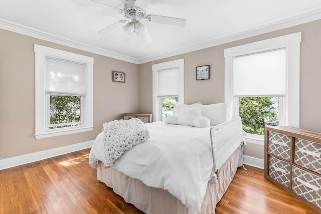 bedroom featuring crown molding, baseboards, ceiling fan, and wood finished floors