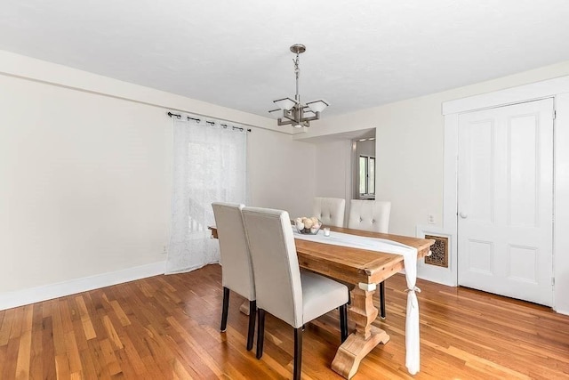 dining space featuring light wood-style floors, baseboards, and a notable chandelier