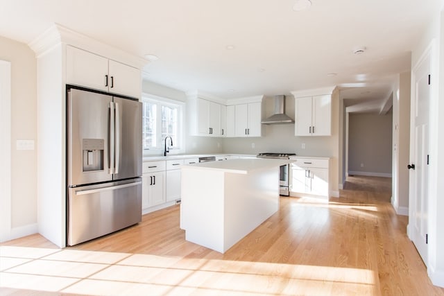 kitchen featuring appliances with stainless steel finishes, a center island, white cabinetry, and wall chimney range hood