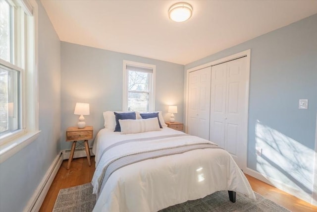 bedroom with baseboard heating, a closet, and wood-type flooring