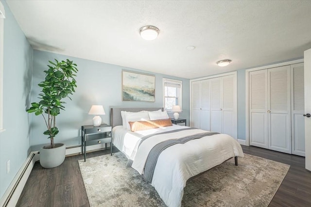 bedroom featuring a textured ceiling, dark hardwood / wood-style floors, a baseboard radiator, and two closets