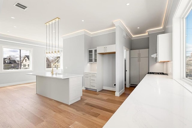 308 Newton St Unit 2, Waltham, MA 02453 - kitchen featuring light wood finished floors, light countertops, a sink, white cabinetry, and crown molding