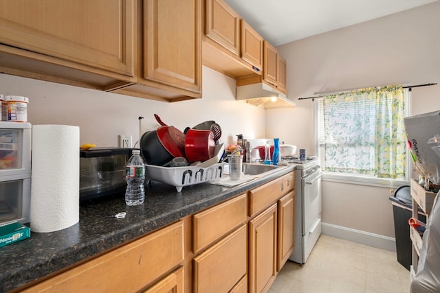 kitchen with dark stone counters, sink, and white range with gas stovetop