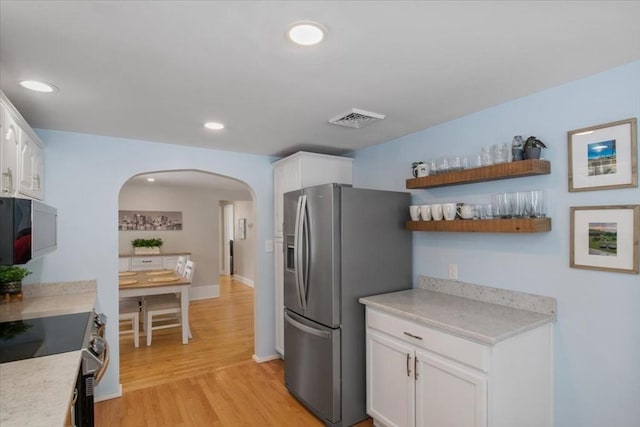 kitchen with visible vents, arched walkways, white cabinets, appliances with stainless steel finishes, and light wood-type flooring