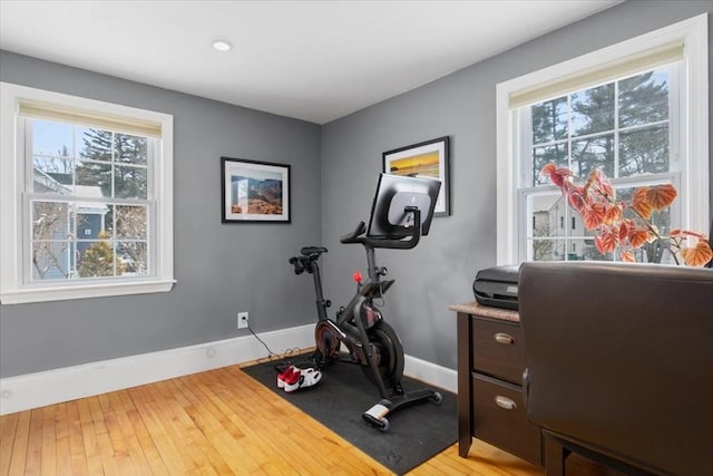 exercise area featuring a healthy amount of sunlight, baseboards, and light wood-style floors