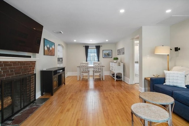 living area with recessed lighting, visible vents, a fireplace, and light wood finished floors