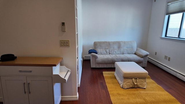 sitting room with baseboards, a baseboard heating unit, and dark wood-type flooring