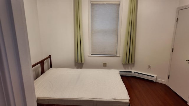 bedroom featuring dark wood-style flooring and a baseboard heating unit
