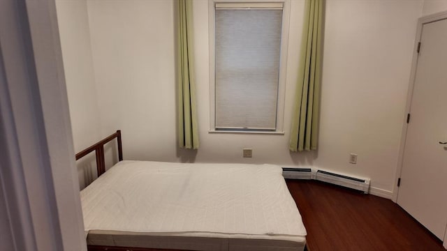 bedroom with a baseboard heating unit and dark wood-style floors