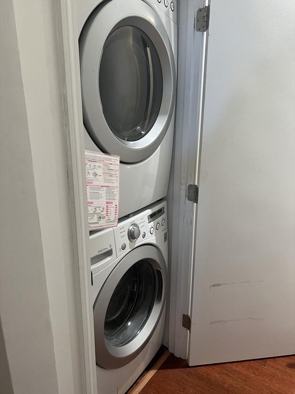 laundry room featuring stacked washing maching and dryer, laundry area, and dark wood-style flooring