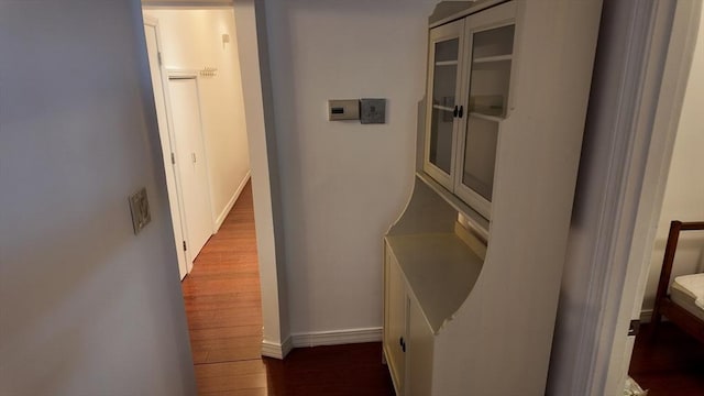 corridor with baseboards and wood finished floors