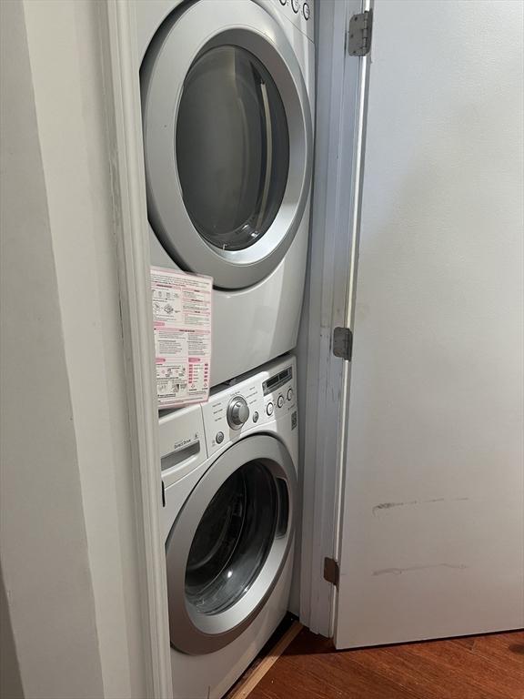 laundry area featuring laundry area, dark wood finished floors, and stacked washer / drying machine