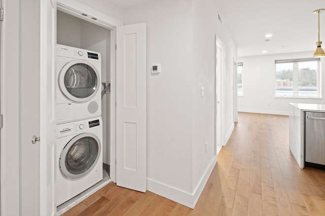 laundry room featuring light hardwood / wood-style floors and stacked washer and clothes dryer