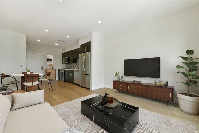 living room featuring recessed lighting, baseboards, and light wood finished floors
