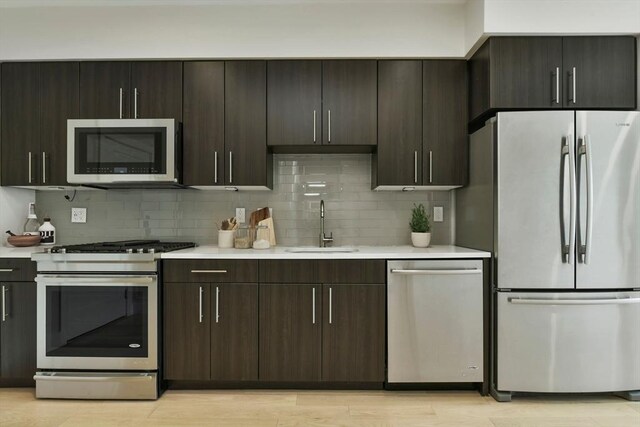 kitchen featuring light countertops, a sink, decorative backsplash, and stainless steel appliances