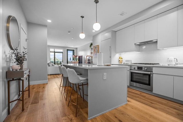 191 Washington St Unit 308, Boston, MA 02135 - kitchen featuring appliances with stainless steel finishes, recessed lighting, a breakfast bar area, light wood finished floors, and tasteful backsplash