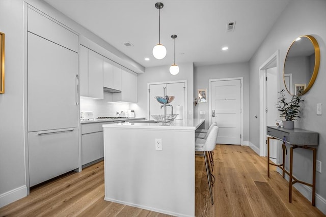 191 Washington St Unit 308, Boston, MA 02135 - kitchen with light wood-type flooring, light countertops, recessed lighting, decorative light fixtures, and a kitchen breakfast bar