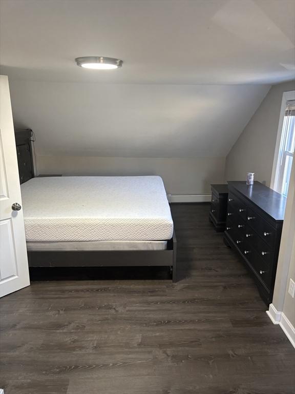 bedroom with lofted ceiling, dark wood-type flooring, and a baseboard radiator