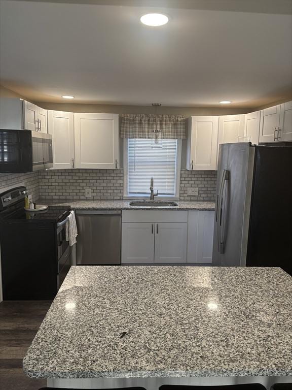 kitchen featuring light stone counters, stainless steel appliances, white cabinetry, and sink