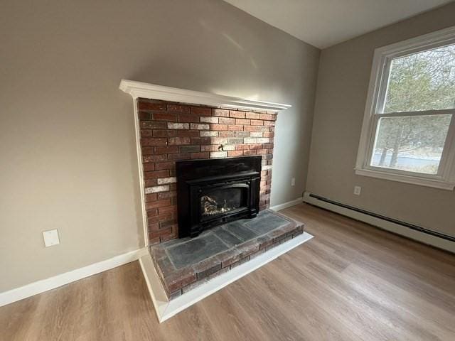 room details featuring baseboard heating, wood-type flooring, and a fireplace