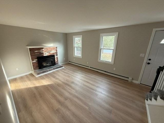 unfurnished living room featuring a fireplace, a baseboard radiator, and light hardwood / wood-style floors