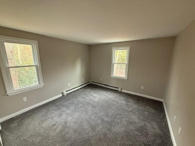 spare room featuring dark carpet and a baseboard heating unit