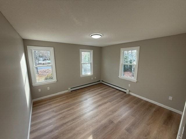 unfurnished room featuring a baseboard heating unit and light wood-type flooring