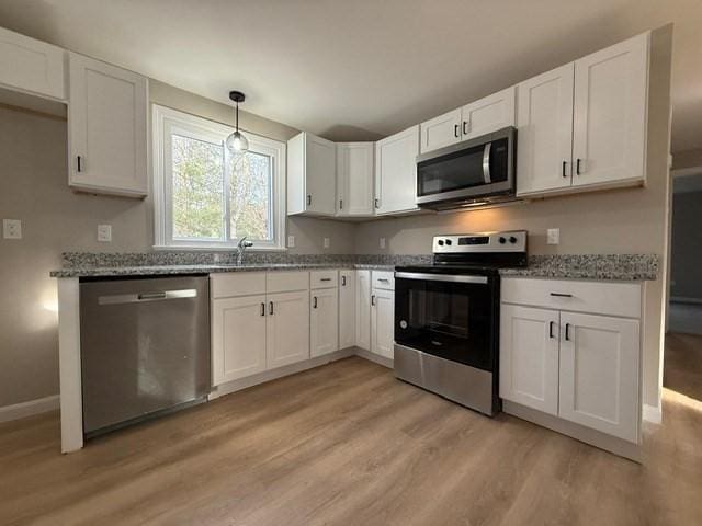 kitchen with stainless steel appliances, white cabinetry, and light wood-type flooring