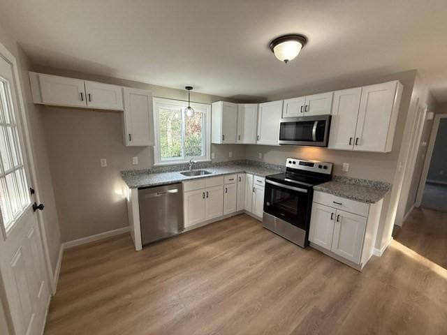 kitchen featuring light stone counters, stainless steel appliances, and white cabinets