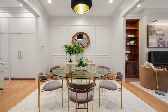 dining space with crown molding, light parquet floors, and built in shelves