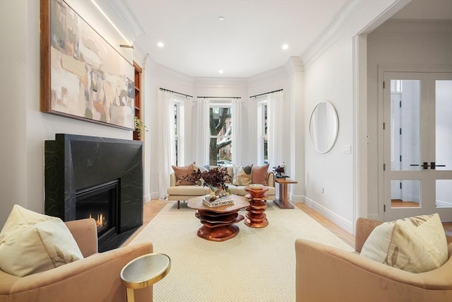 living room featuring ornamental molding, light wood-type flooring, a fireplace, and french doors