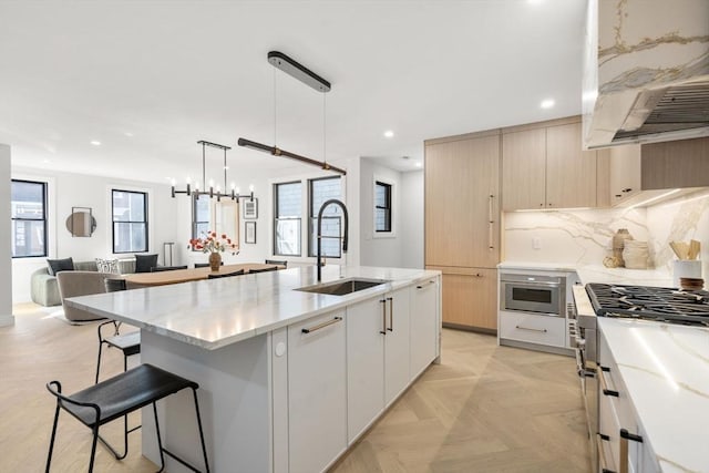 kitchen with a sink, backsplash, ventilation hood, and modern cabinets