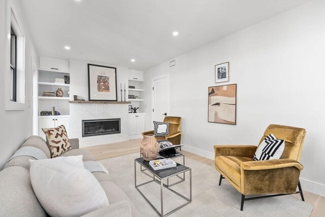 living room featuring light wood-style floors, a fireplace, baseboards, and recessed lighting