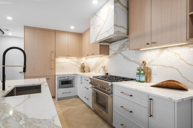 kitchen with a sink, high end range, custom exhaust hood, and light stone countertops