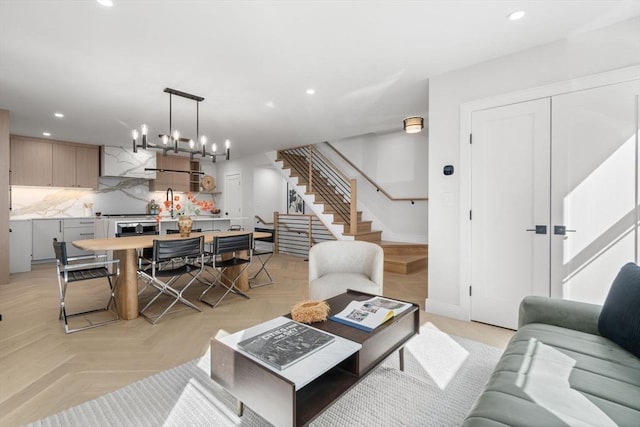 living room with recessed lighting, baseboards, an inviting chandelier, and stairs