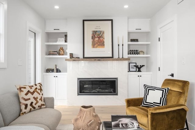 sitting room featuring a premium fireplace, recessed lighting, and built in features