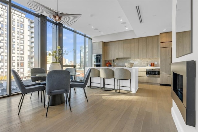 dining room featuring floor to ceiling windows, a city view, recessed lighting, visible vents, and light wood-type flooring