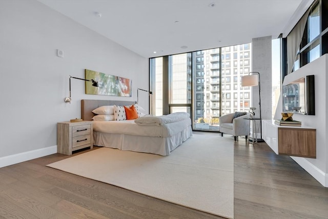 bedroom with expansive windows, baseboards, and wood finished floors