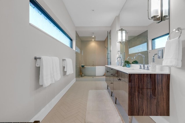 full bathroom with a sink, plenty of natural light, baseboards, and a freestanding bath