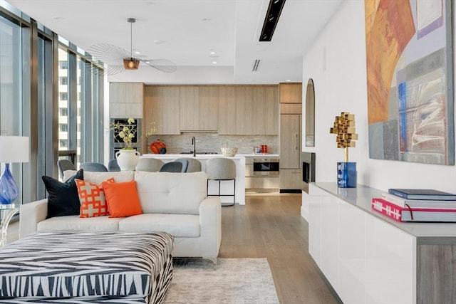 living room with light wood finished floors, a wall of windows, and visible vents