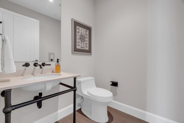 bathroom featuring a sink, wood finished floors, toilet, and baseboards